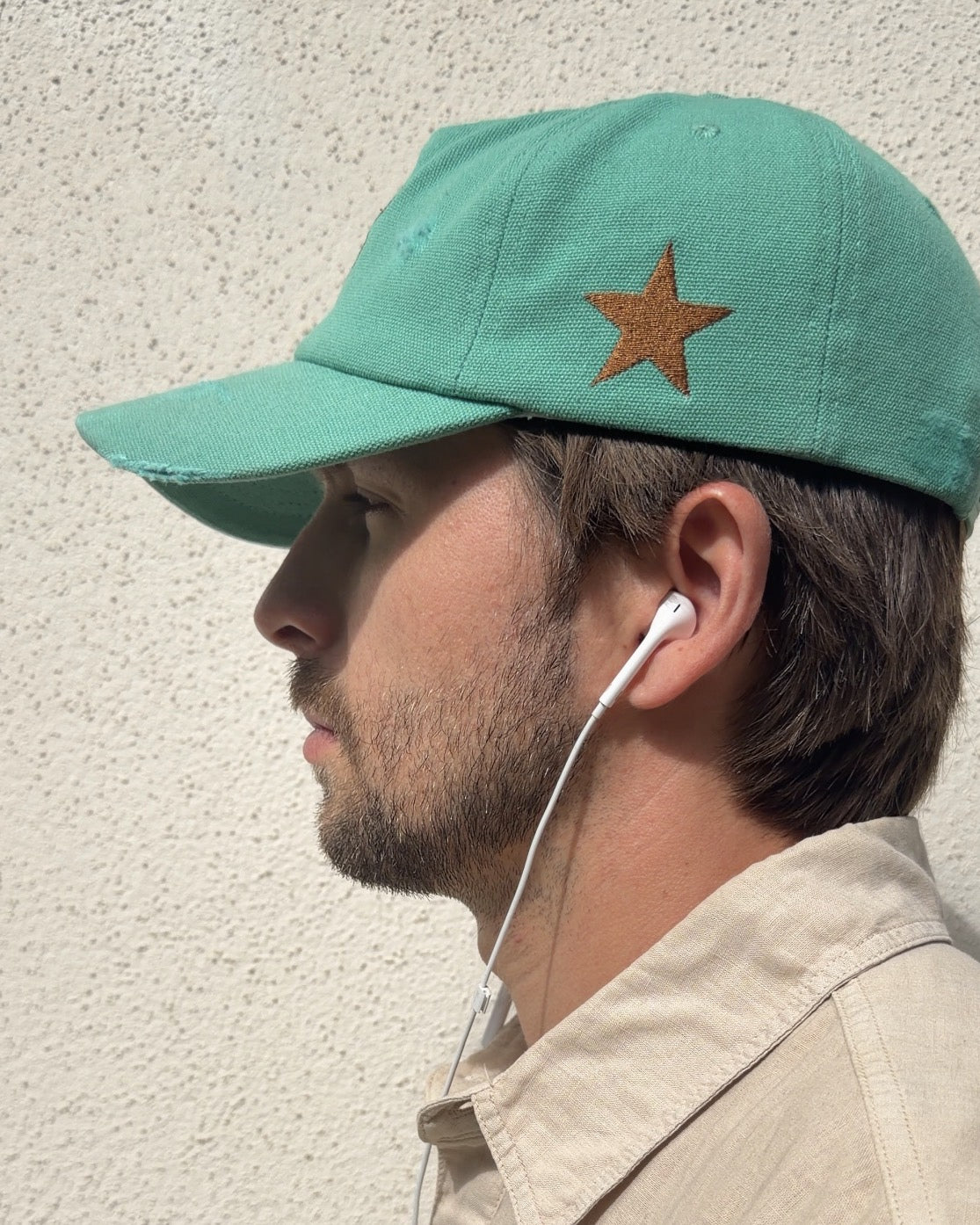 Good Luck Out There cap worn in the sun, side profile showing the copper embroidered star and distressed brim