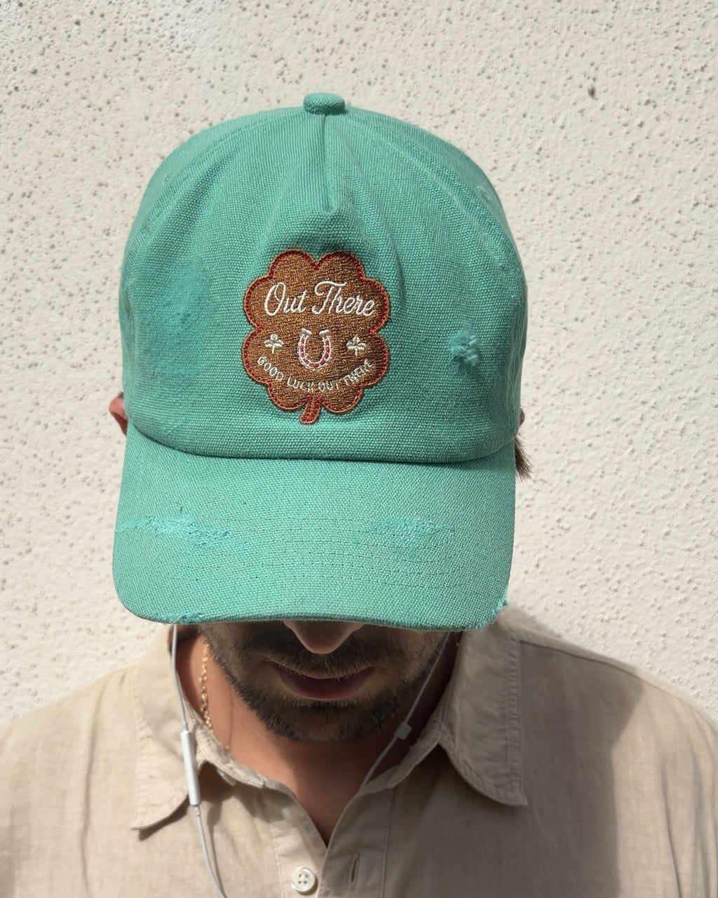 Good Luck Out There cap worn head-down, showing the clover patch and distressed seafoam canvas