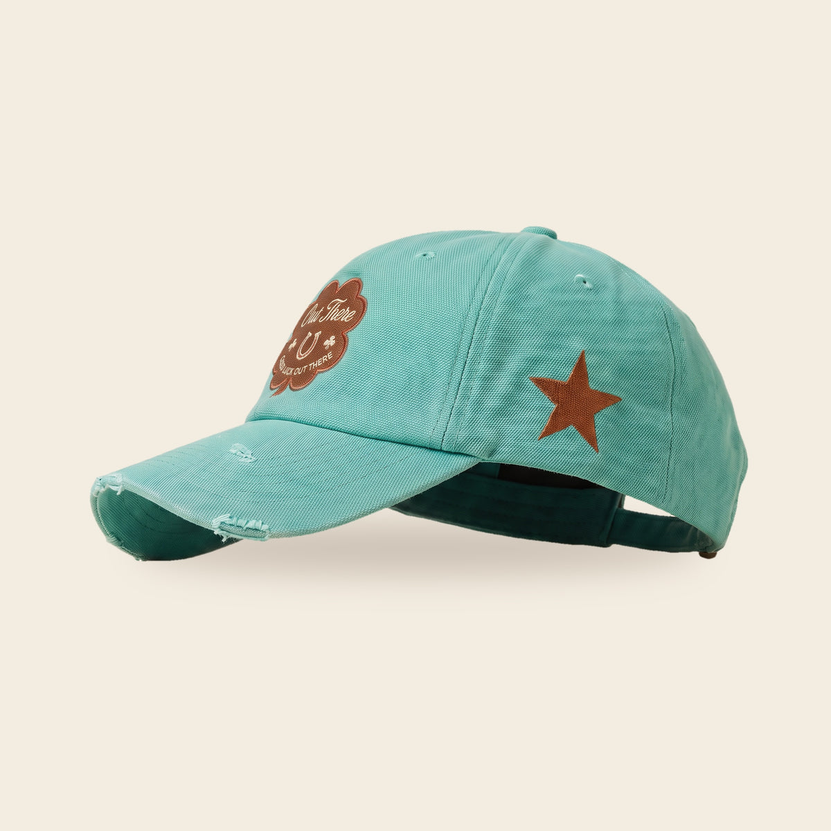 Good Luck Out There cap in seafoam canvas, side profile with the clover patch on the front, copper star on the side and hand distressed brim